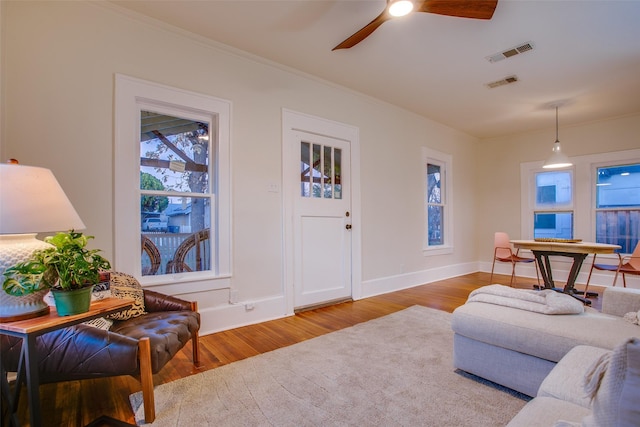 living room featuring ceiling fan, ornamental molding, and hardwood / wood-style flooring