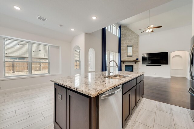 kitchen featuring stainless steel appliances, vaulted ceiling, sink, a center island with sink, and light hardwood / wood-style flooring