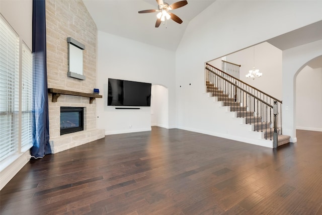 unfurnished living room featuring a large fireplace, dark hardwood / wood-style flooring, high vaulted ceiling, and ceiling fan with notable chandelier