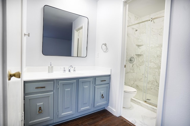 bathroom featuring vanity, toilet, a shower with door, and wood-type flooring