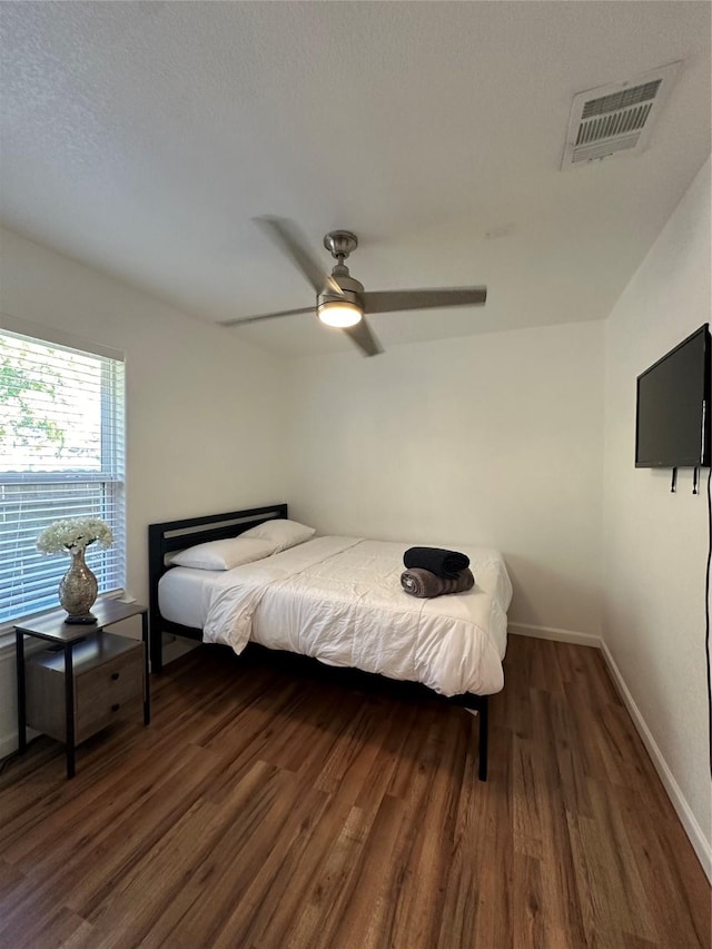 bedroom with ceiling fan, dark hardwood / wood-style flooring, and a textured ceiling