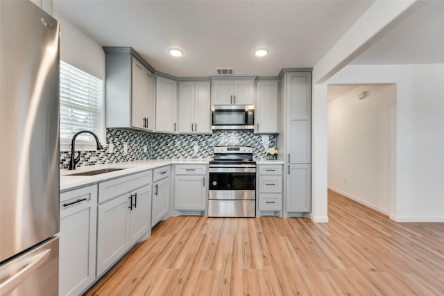 kitchen featuring gray cabinets, sink, stainless steel appliances, and light hardwood / wood-style flooring