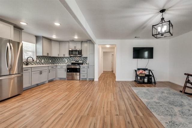 kitchen featuring appliances with stainless steel finishes, gray cabinets, light hardwood / wood-style flooring, and pendant lighting