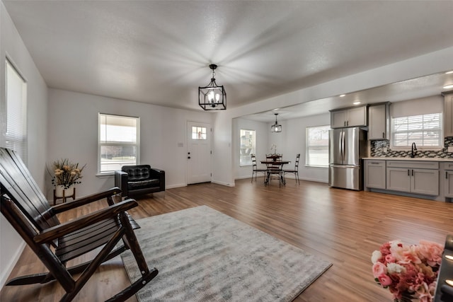 living room featuring hardwood / wood-style floors, a wealth of natural light, a notable chandelier, and sink