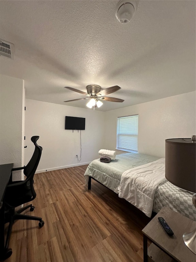 bedroom with ceiling fan, wood-type flooring, and a textured ceiling