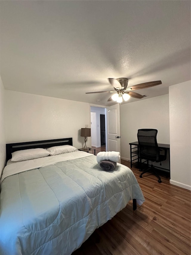 bedroom with a textured ceiling, ceiling fan, and dark wood-type flooring