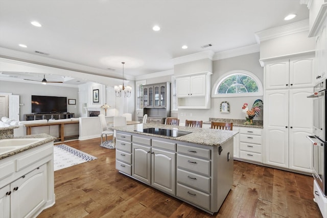 kitchen with white cabinetry, a kitchen island, hanging light fixtures, and dark hardwood / wood-style floors