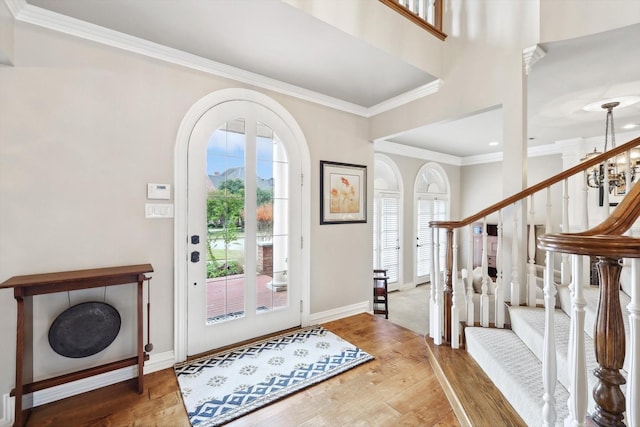 foyer entrance featuring hardwood / wood-style flooring, ornamental molding, and a chandelier