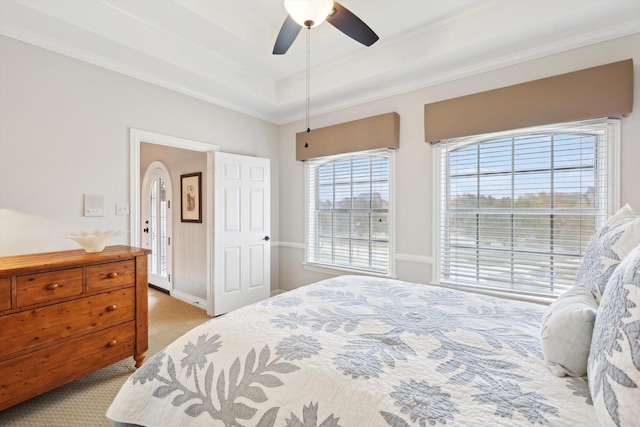 carpeted bedroom featuring ceiling fan, a raised ceiling, and crown molding