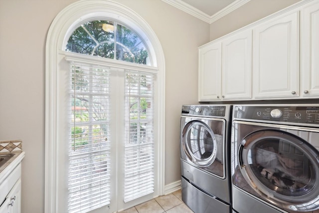 clothes washing area with cabinets, light tile patterned floors, washer and clothes dryer, and crown molding