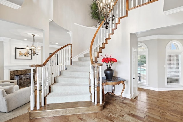 stairway with wood-type flooring, a towering ceiling, and ornamental molding