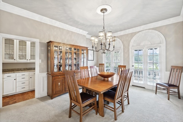 carpeted dining room with ornamental molding and a notable chandelier