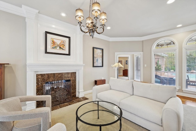 living room featuring a tile fireplace, wood-type flooring, an inviting chandelier, and ornamental molding