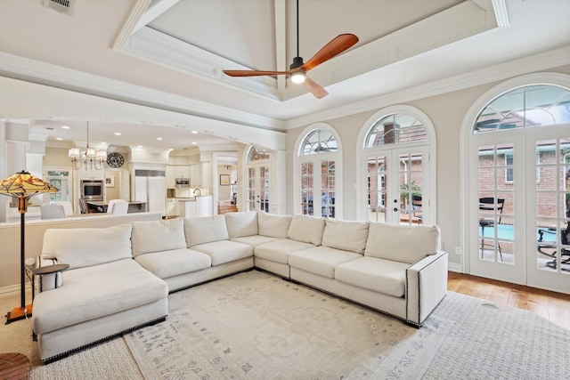 living room with ceiling fan with notable chandelier, light hardwood / wood-style floors, crown molding, and french doors