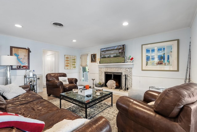 living room with a premium fireplace, ornamental molding, and light hardwood / wood-style floors