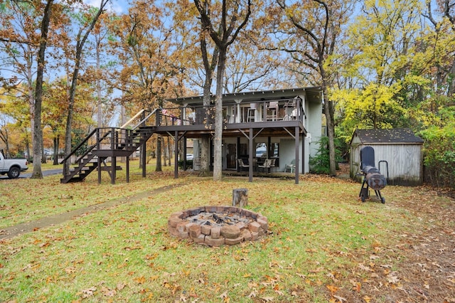 back of property featuring a shed, an outdoor fire pit, a lawn, and a wooden deck