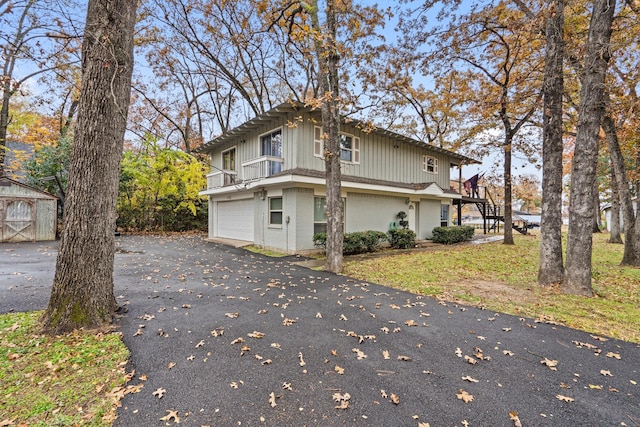 view of property exterior with a balcony, a garage, and a storage unit