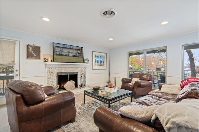 living room with crown molding, plenty of natural light, wood-type flooring, and a high end fireplace