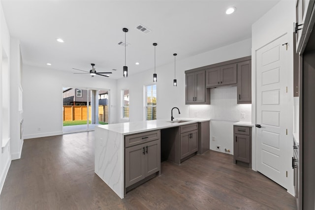 kitchen with dark wood-type flooring, sink, ceiling fan, decorative light fixtures, and kitchen peninsula