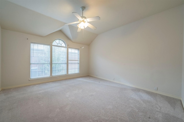 carpeted spare room with ceiling fan and vaulted ceiling