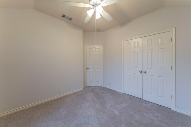 unfurnished bedroom with vaulted ceiling, a closet, ceiling fan, and carpet flooring