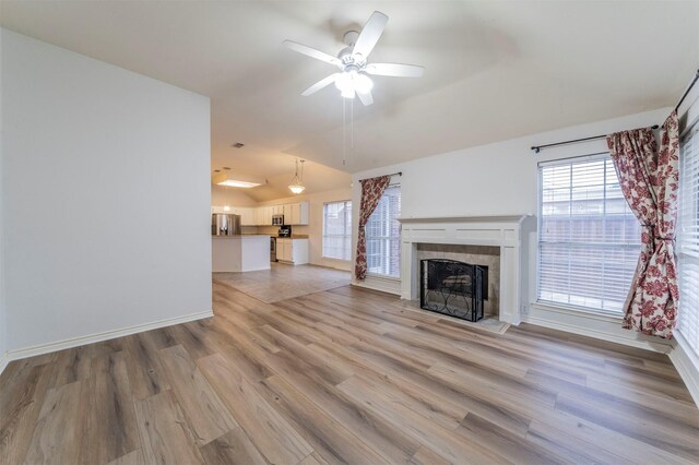 unfurnished living room with ceiling fan, lofted ceiling, light hardwood / wood-style floors, and a tile fireplace