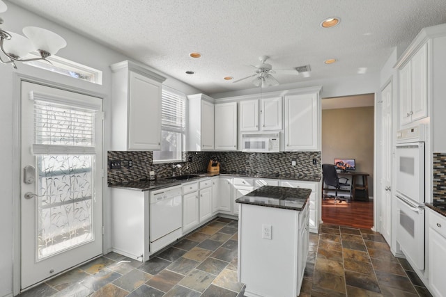 kitchen featuring white cabinets, a center island, and white appliances