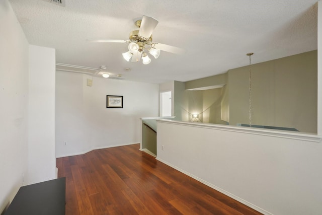 spare room with a textured ceiling, ceiling fan, and dark wood-type flooring