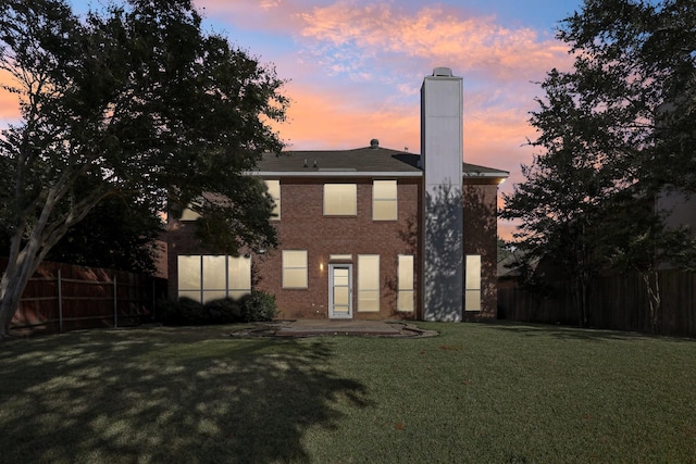 back house at dusk featuring a yard