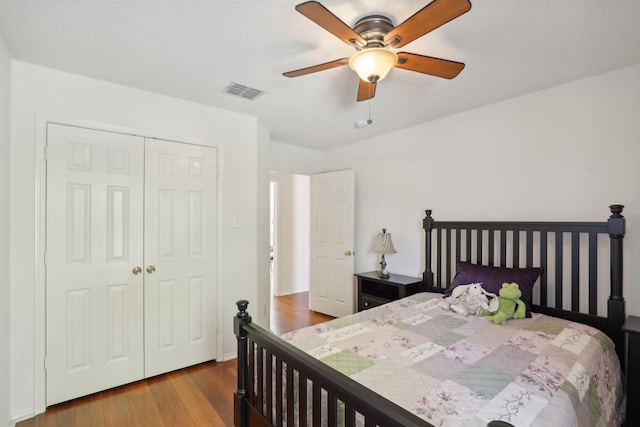 bedroom with a textured ceiling, a closet, hardwood / wood-style flooring, and ceiling fan