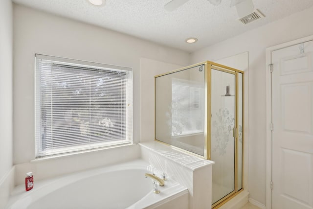 bathroom with a textured ceiling, separate shower and tub, and ceiling fan