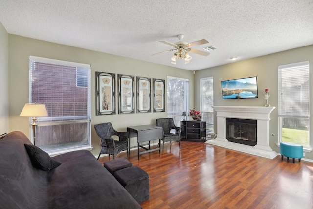 living room featuring wood-type flooring, a textured ceiling, and ceiling fan