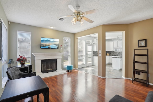 living room with hardwood / wood-style floors, ceiling fan with notable chandelier, and a textured ceiling