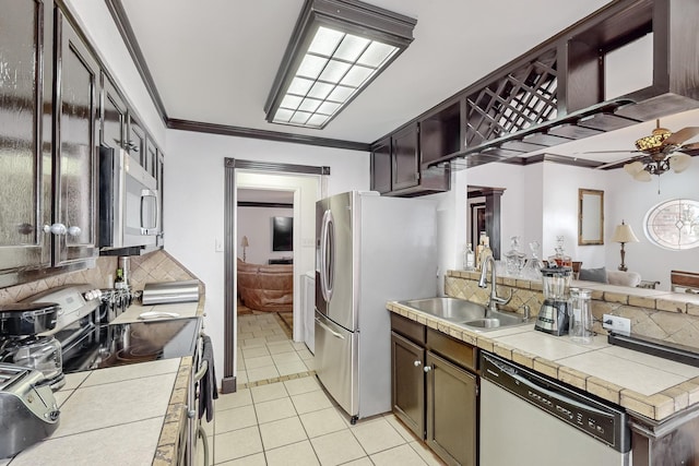 kitchen with appliances with stainless steel finishes, sink, backsplash, tile counters, and crown molding