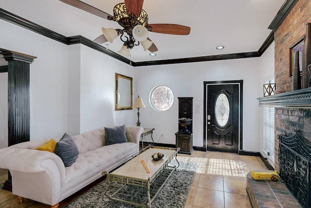 living room with tile patterned flooring, a brick fireplace, ornamental molding, ceiling fan, and decorative columns