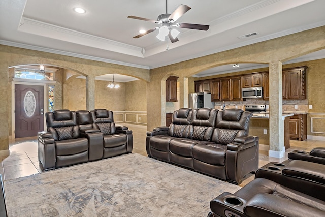 tiled home theater featuring ceiling fan with notable chandelier, ornamental molding, and a tray ceiling