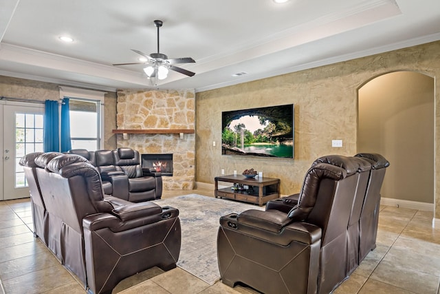 living room featuring crown molding, a fireplace, a tray ceiling, and ceiling fan