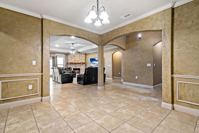 interior space with ornamental molding, ceiling fan with notable chandelier, a fireplace, and light tile patterned flooring