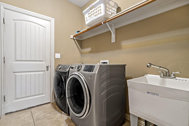 laundry room featuring light tile patterned flooring, sink, and washing machine and dryer