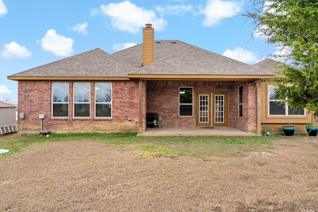 rear view of property featuring french doors, a lawn, and a patio area