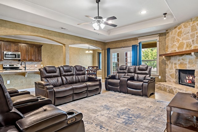 tiled living room featuring crown molding, a fireplace, and a raised ceiling