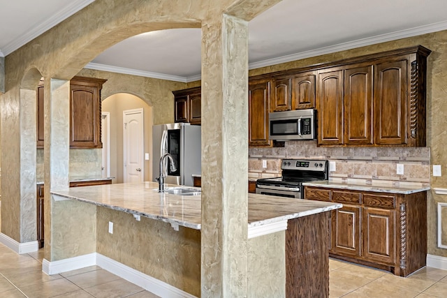 kitchen with light stone countertops, appliances with stainless steel finishes, sink, light tile patterned floors, and an island with sink