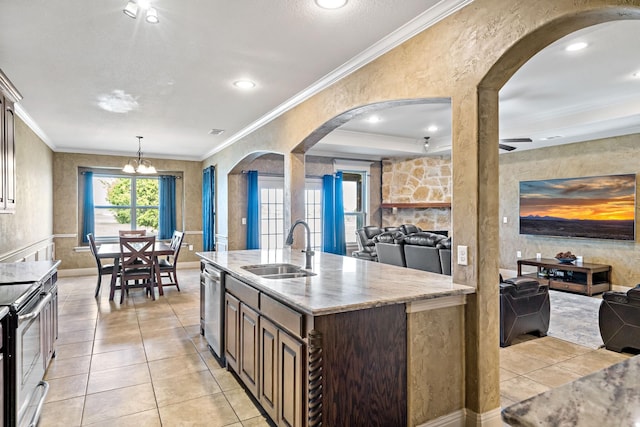 kitchen featuring stainless steel appliances, light tile patterned flooring, sink, and a kitchen island with sink