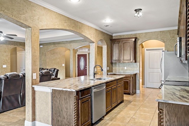 kitchen with sink, stainless steel appliances, ornamental molding, and an island with sink