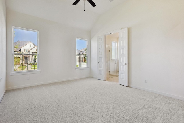 unfurnished bedroom with ceiling fan, vaulted ceiling, light carpet, and multiple windows