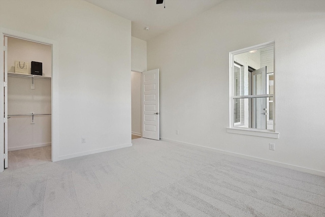 unfurnished bedroom featuring a spacious closet, a closet, and light carpet