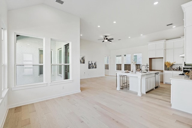 kitchen featuring dishwasher, white cabinetry, sink, a kitchen island with sink, and light hardwood / wood-style floors