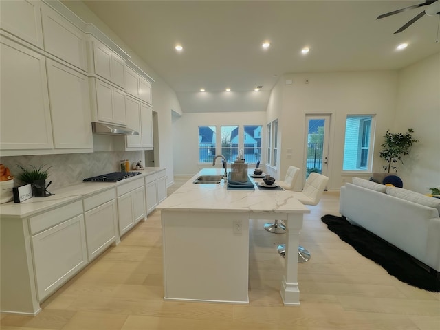 kitchen with a center island with sink, stainless steel gas stovetop, white cabinetry, and sink