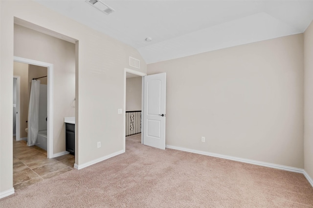 unfurnished bedroom featuring light colored carpet and vaulted ceiling