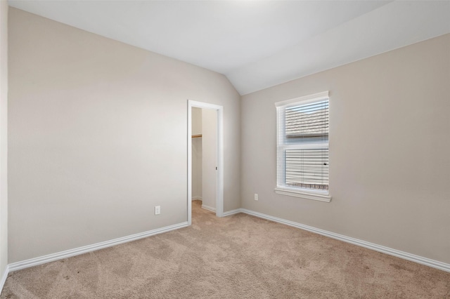 carpeted empty room featuring vaulted ceiling